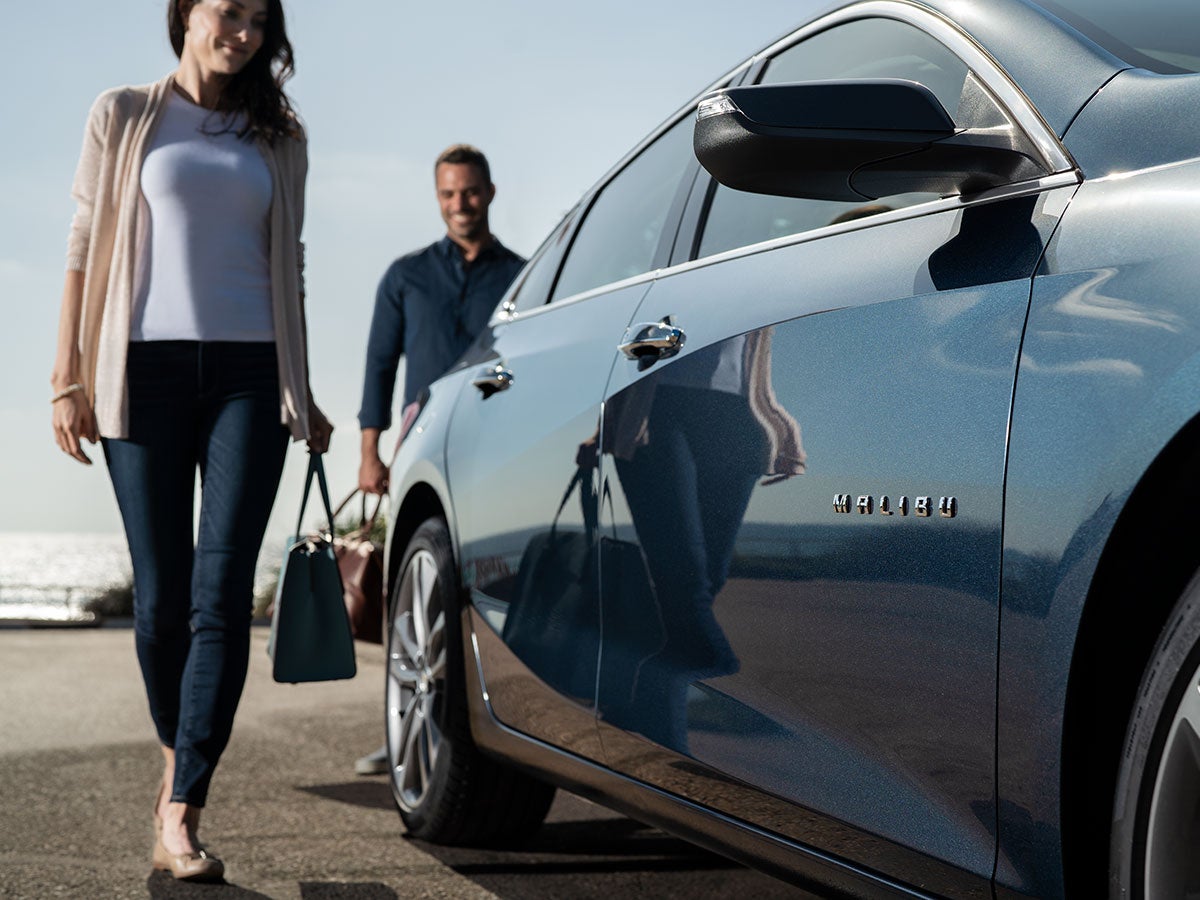 woman and man standing chevy malibu