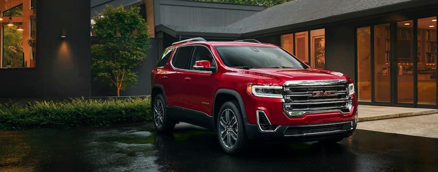 A red 2023 GMC Acadia parked on a driveway after leaving a GMC dealer.